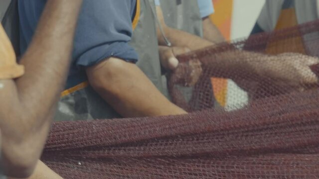 Team of men haul up fishing nets from commercial fishing boat on dock Essaouira
