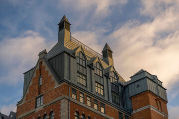 Old 1800s red brick brewery house facades with tin roof, black chimneys, towers and roof dormers a sunny day in the district Södermalm in Stockholm