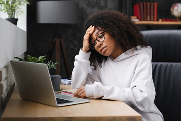 Tired exhausted stressed overworked young african woman teenage girl student using laptop, having...