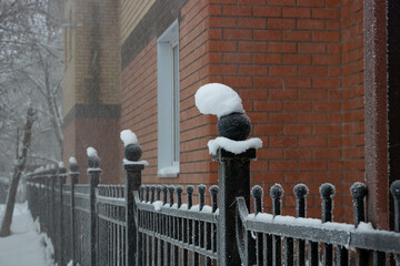 A snow cap on a wrought iron fence after a cold winter blizzard
