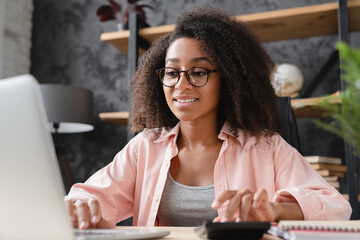 Closeup shot young african student worker businesswoman freelancer counting funds domestic bills on...