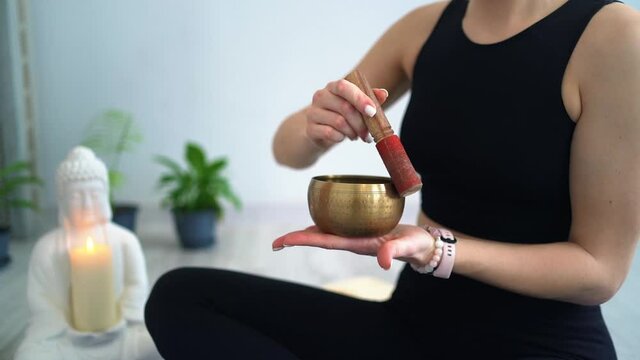 Young woman practicing yoga and meditation with singing bowl sitting on floor Video HD