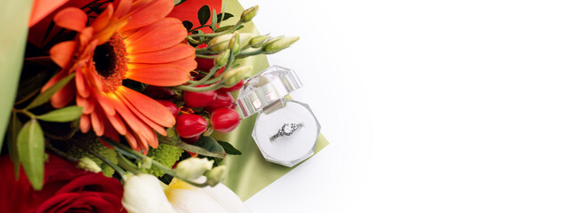 Engagement ring in a gift box with bright bouquet of flowers. The offer to get married. Gift for...