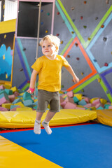cute blond little boy jumps in a trampoline park, children activity