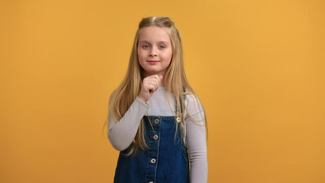 Portrait smiling mystery girl showing shh quiet gesture finger near mouth posing isolated on orange 