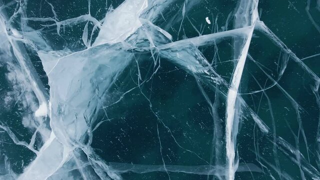 Frozen Lake Baikal, Aerial view. Beautiful winter landscape with clear smooth ice. Famous natural landmark Russia. Blue transparent ice with deep cracks, top view of a frozen lake.