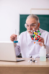 Old male teacher chemist in the classroom