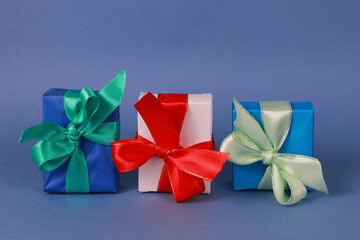 Three multicolored gift boxes on blue background.