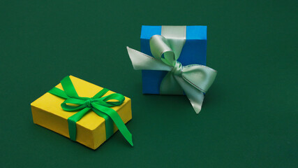 Yellow and blue paper boxes with bows on green background.