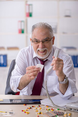 Old drug addicted employee sitting in the office