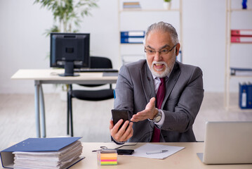 Obraz premium Old male employee sitting in the office