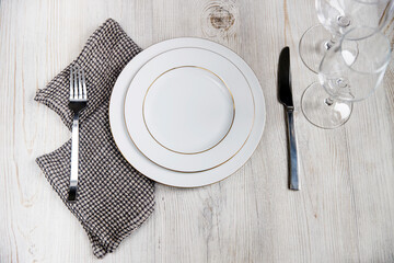 Serving plate, spoon, fork, knife and grey napkin are on the wooden table