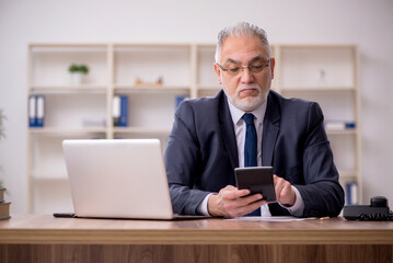 Old male bookkeeper sitting in the office