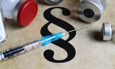 Closeup of paragraph symbol with vaccination serum injection syringe and vials - mandatory...