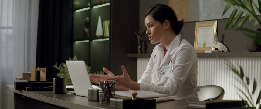 Portrait of Caucasian female doctor delivering telemedicine consultation to a patient from her office. Telehealth, telemedicine, remote consultation service. Coronavirus, COVID-19
