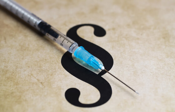 Closeup of paragraph symbol with vaccination injection syringe - euthanasia assisted suicide dying concept