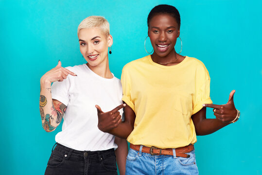 Speak Your Truth. Studio Shot Of Two Confident Young Women Pointing At Their T Shirts Against A Turquoise Background.