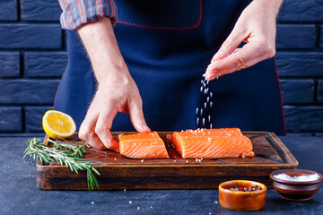 Man is sprinkling salt over salmon fillet