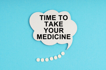 On a blue table are pills and a white plate with the inscription - Time to take your medicine