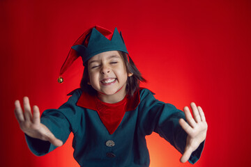 boy child in a dwarf costume stands on red background on Christmas Day