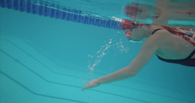 Woman swimmer swims in water style crawl under water, training in the pool. Woman in goggles trains in the pool, preparing for a competition. Professional training in the pool. 4k, ProRes