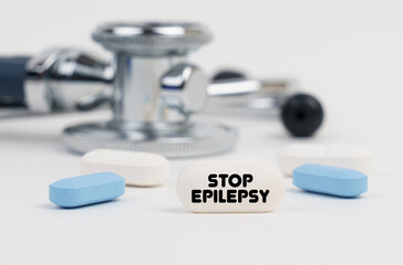 On a white surface lie pills, a stethoscope and a tablet with the inscription - STOP EPILEPSY