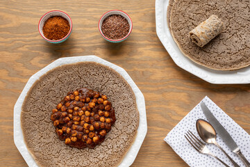 Injera traditional Ethiopian sourdough ferment flatbread with spicy chickpea stew with flaxseed sauce. Top view.