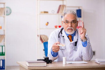 Old male doctor working in the clinic