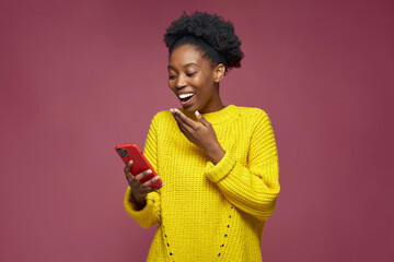 Laughing african american girl hold phone watching funny videos in social network, having fun,...