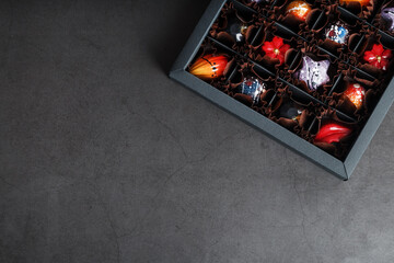 Handmade chocolates in a box on a dark background.