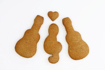 Gingerbreads in a shape of guitar, treble clef and heart on white background. Musical concept, love of music