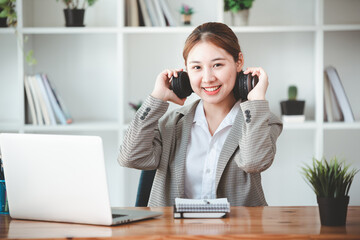 asian girl happy and charming Wear headphones to communicate by video conferencing at your desk. Using a laptop computer, video chat