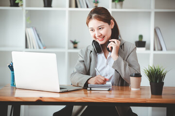 asian girl happy and charming Wear headphones to communicate by video conferencing at your desk. Using a laptop computer, video chat