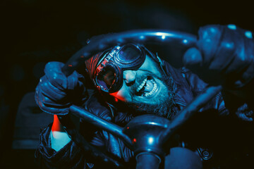 Naklejka premium Old school retro image of crazy driver with beard wearing vintage glasses and leather helmet while holding on to the steering wheel.