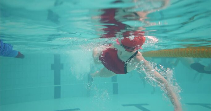 Woman swims underwater in goggles, fitness classes in the pool. Young woman trains, swims in a crawl style, bubbles under water. 4k, ProRes