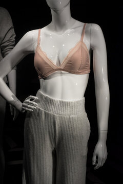Closeup of beige satin bra and pyjama pants on mannequin in fashion store showroom for women
