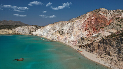 Aerial drone view of iconic volcanic white chalk sandy organised with sun beds and umbrellas beach of Firiplaka with turquoise clear sea and rocky colour formations, Milos island, Cyclades, Greece