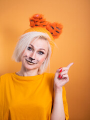 A girl with tiger makeup on an orange background. Funny smiling. Tiger new year celebration