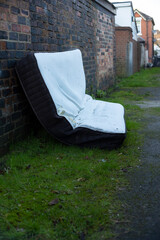 a mattress dumped in a alley way at the back of some houses