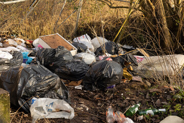 pile of garbage bags dumped illegally on some spare ground 