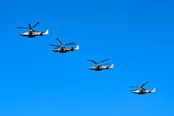 Military helicopters are flying in the sky .