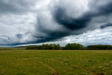 a dark black shelf cloud in a foreboding dark grey thunder storm cloud sky bringing heavy rain over...