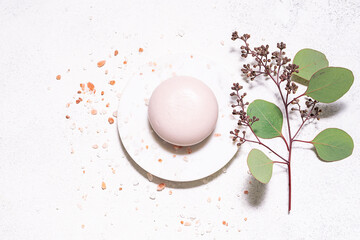 Natural soap on the marble round podium with Himalaya salt and fresh eucalyptus branch top view....
