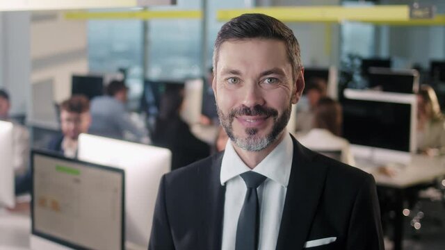 Portrait of cheerful male boss in suit with beard looking to camera and smiling. Good looking caucasian man team leader in modern company office.