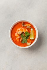 White bowl of fresh Tom Yum soup on a light background