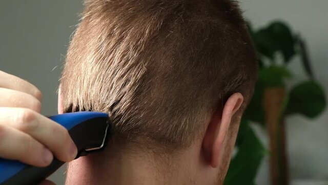 A man is getting a haircut with an electric clipper at home. Home haircut. Savings on hairdresser.