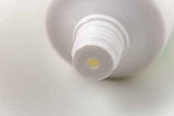 The white tube of toothpaste is open. The thread of the neck of a white tube close-up.