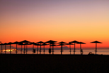sunset at the beach with sun umbrellas 