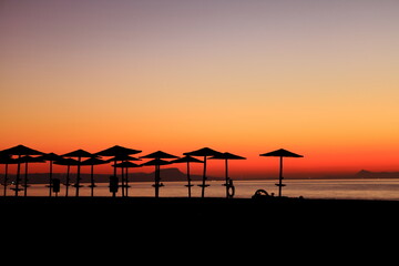 sunset at the beach with sun umbrellas 