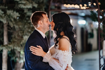 gentle and happy bride and groom in wedding dresses on the evening street.